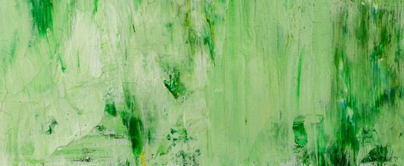 Smeared green paint on a wall with cracks and spots of white paint