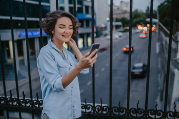 attractive stylish woman walking in street using smartphone