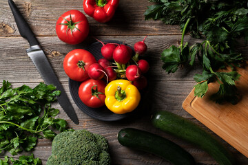 A lot of fresh vegetables from the frocery farm shop exposed on the vintage wooden table with chopping board.