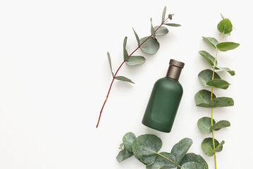 Perfume bottle with green eucalyptus branches isolated on white background. Beauty concept, mockup © vladdeep
