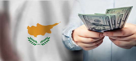 100 us dollar banknotes in human hands on flag of Republic of Cyprus background