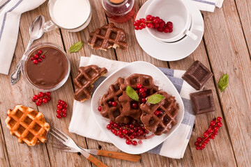 Waffles with chocolate topping, red currant and hazelnuts.