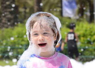 Children's foam party. The boy plays in the foam. Concept: birthday, animators, party.