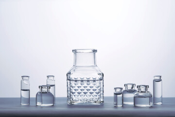 Different bottles of water on a light background. It can fit the theme of cosmetics, glass and freshness.