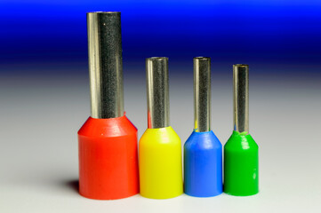 Four colorful ferrules standing in a row on a white background with a blue backlight - macro photo.