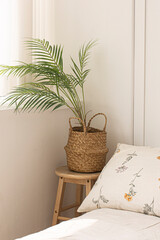 wooden bedside table on palm flowerpot with bed.