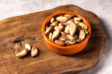 Brazil nut in ceramic bowl on a kitchen board.
