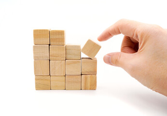 stack of blank wooden cube block with hand about to pick one of wooden block , isolated on white background 