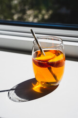 Ein Glas Eistee mit Pfirsich auf einem weißen Fensterbrett im Sonnenlicht. Schlagschatten, Sommer Getränk.
