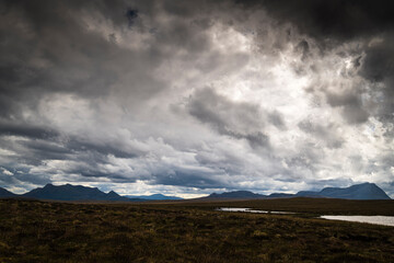 A gloomy, summer, HDR landscape image of Ben Loyal and Ben Hope across a boggy morass with Ben...