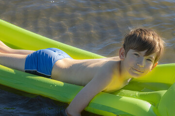 Boy is sleeping on an inflatable mattress in the water. The child alone in the water. A young man...