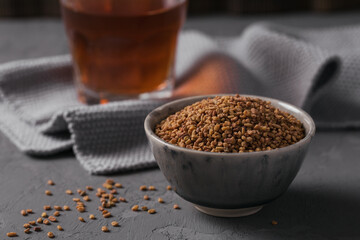 Bowl of fenugreek seeds and Egyptian fenugreek yellow tea or Methi Dana drink on grey background