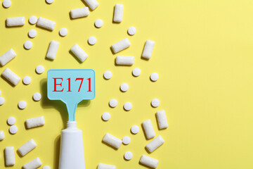 Titanium dioxide, E171, dangerous additive concept. gum, pills, toothpaste or cream and sign with E171 on yellow background. copy space