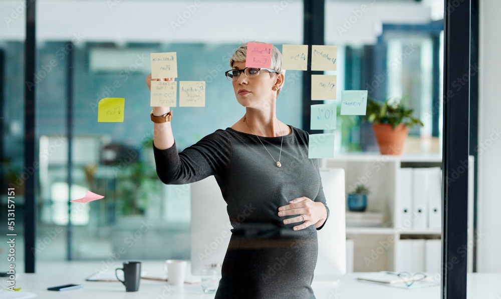 Poster getting a few ideas rolling for a new project. shot of a pregnant businesswoman brainstorming with n
