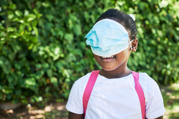 Is it an eye mask. Shot of a little girl covering her eyes with a mask in nature.