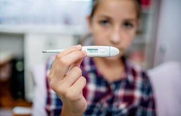 High temperature. Sick little girl measuring temperature with thermometer, close up photo. Medical, health care concept