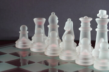 Chess with game pieces made of glass, queen, king, pawn and game board made of glass in black and...