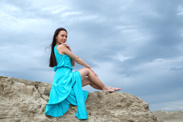Fototapeta na wymiar beautiful brunette girl in a bright blue dress in the desert.