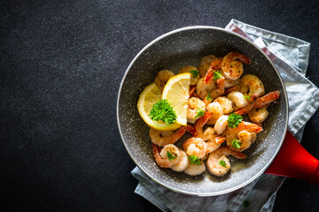 Frying shrimps with lemon in the frying pan.