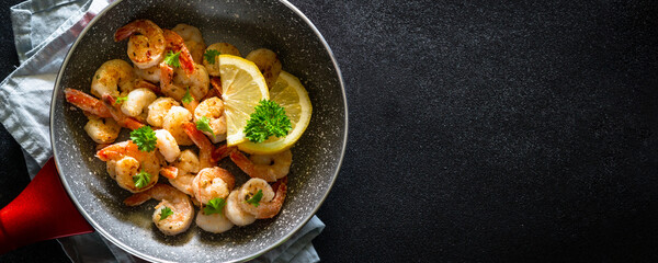 Frying shrimps with lemon in the frying pan.