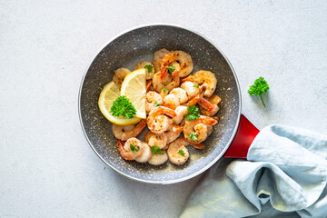 Frying shrimps with lemon in the frying pan.