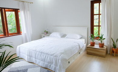 Minimal bedroom with wooden floor, white bed and plantsใ