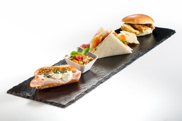 Black stone rectangular tray with snack Pretzel turkey flaky cheese sandwiches salmon pearl spelled vegetables milk sandwiches omelette