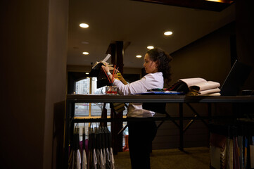 Naklejka premium Inspired freelance interior designer holding fabric swatches of various texture and quality and browsing colorful textiles for new home design project