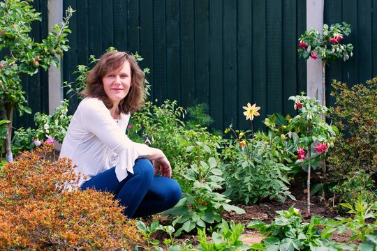 Woman in the garden, with standard fuchsias and dahlias.