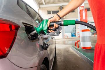 Woman refueling gasoline at gas station in fuel crisis. gray car