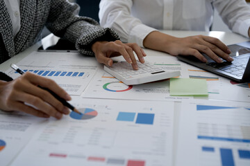 Business people using calculator and laptop computer for discussion about profit, tax, financial