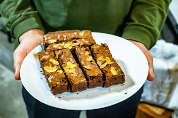 close-up view of hands holding a banana cake with chocolate on white plate