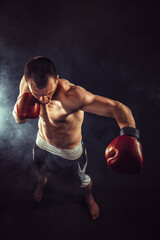 Plakat Muscular kickbox or muay thai fighter punching in smoke