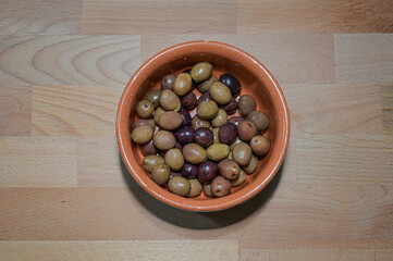 Olive in una ciotola di terracotta sopra una tavola di legno