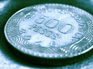 Translation: 500 Colombian pesos Republic of Colombia. Colombian coin 500 pesos close-up. Peso of Colombia. Blue tinted illustration for news about economy or banking. Loan and credit. Macro