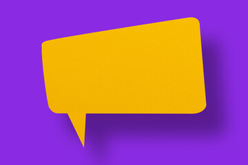 Speech balloon shaped yellow paper against a purple background.