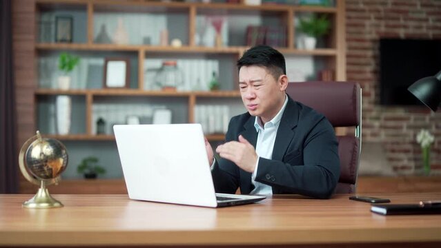 Dissatisfied with the results businessman looking at laptop computer screen in the office. Angry middle aged asian business man lawyer attorney analyst manager banker boss bad work fail and failure