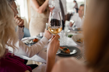 a glass of white wine in a girl's hand in a restaurant