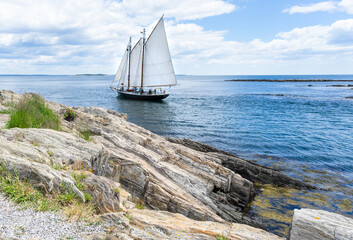 A landscape view of a sailboat on the in the Atlantic Ocean off of the coast of Maine