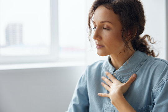 Serious irritated anxious angry curly-haired businesswoman is trying to calm down doing breathing exercises from psychotherapy after being insulted by her superiors in social networks read on laptop