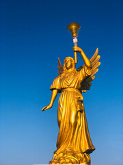 Angel statue standing against blue sky background.