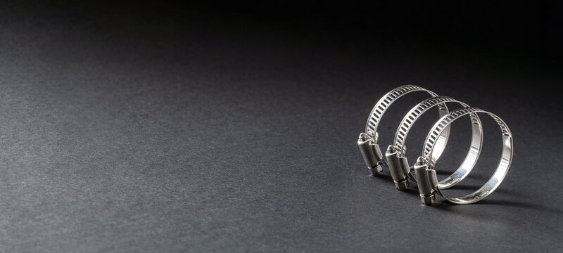 Metal hose clamp on black background. Empty space for text