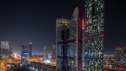 Naklejka premium Aerial view of Dubai International Financial District with many skyscrapers night timelapse.