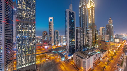 Fototapeta premium Aerial view of Dubai International Financial District with many skyscrapers day to night timelapse.