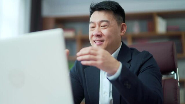 Asian businessman communicates on a video call online talk remotely use laptop computer in office. Conference meeting. male employee in formal suit. successful business man conversation, working. Asia