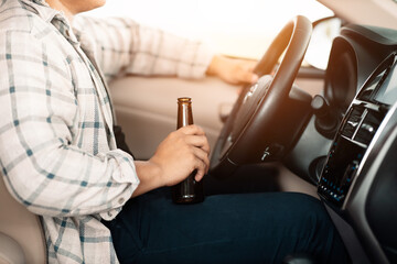Drunk man holding bottle of beer while driving a car, campaigning for drunken not driving avoiding...