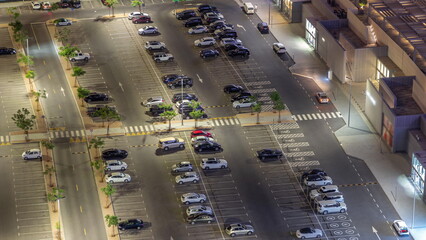 Rows of cars parked in a parking lot between lines viewed from above night timelapse