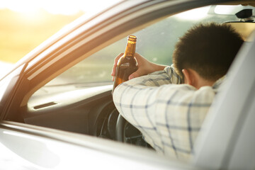 Drunk man holding bottle of beer while driving a car, campaigning for drunken not driving avoiding...