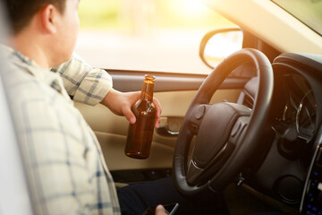 Drunk man holding bottle of beer while driving a car, campaigning for drunken not driving avoiding accidents on road, Don't drink and drive concept.