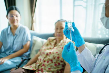 Doctor preparing a vaccine in syringe for injecting on Asian elder woman arm.
